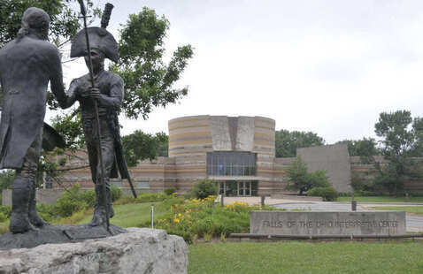 Bronze statues of two explorers stand in front of the Falls of the Ohio Interpretive Center.